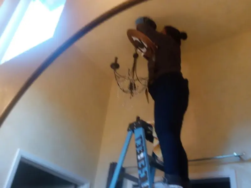 Electrician installing a chandelier in a North College Hill residence